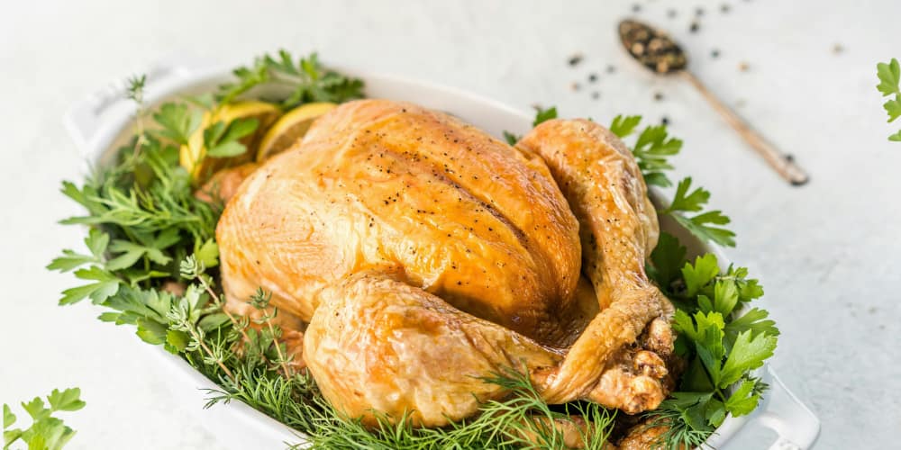 Thanksgiving turkey sitting in a serving dish surrounded by herbs and garnish