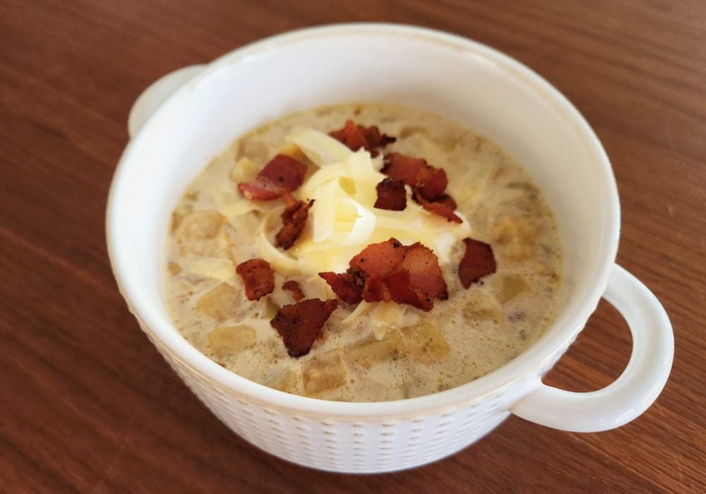 Bowl of cheesy bacon potato soup topped with crispy bacon