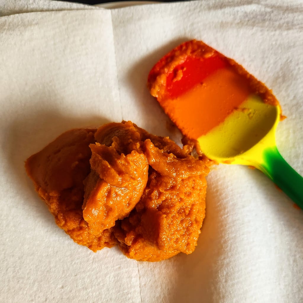 Blotting pumpkin puree on a paper towel to remove excess moisture for baking cookies