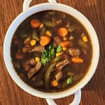 Bowl of soup with beef and vegetables including corn, carrot, green beans and celery