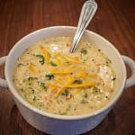 Bowl of creamy soup with broccoli, carrots, and cheddar cheese