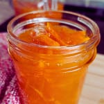 Half-pint mason jar of fresh orange marmalade with thin slices of orange peel and sticky jam