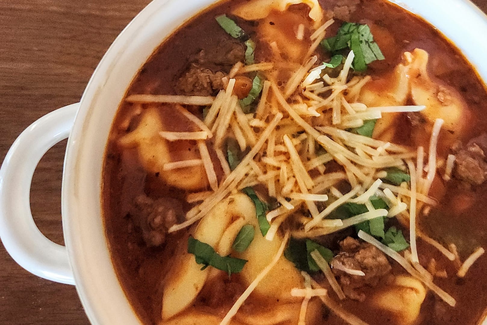 Bowl of sausage and tortellini soup in a tomato-based broth