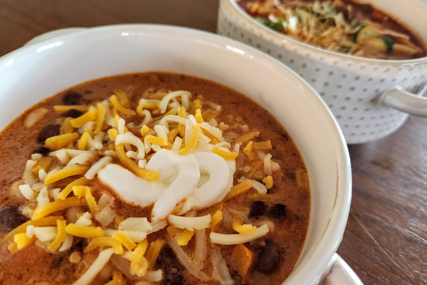 Bowl of chili, topped with sour cream and shredded cheddar cheese