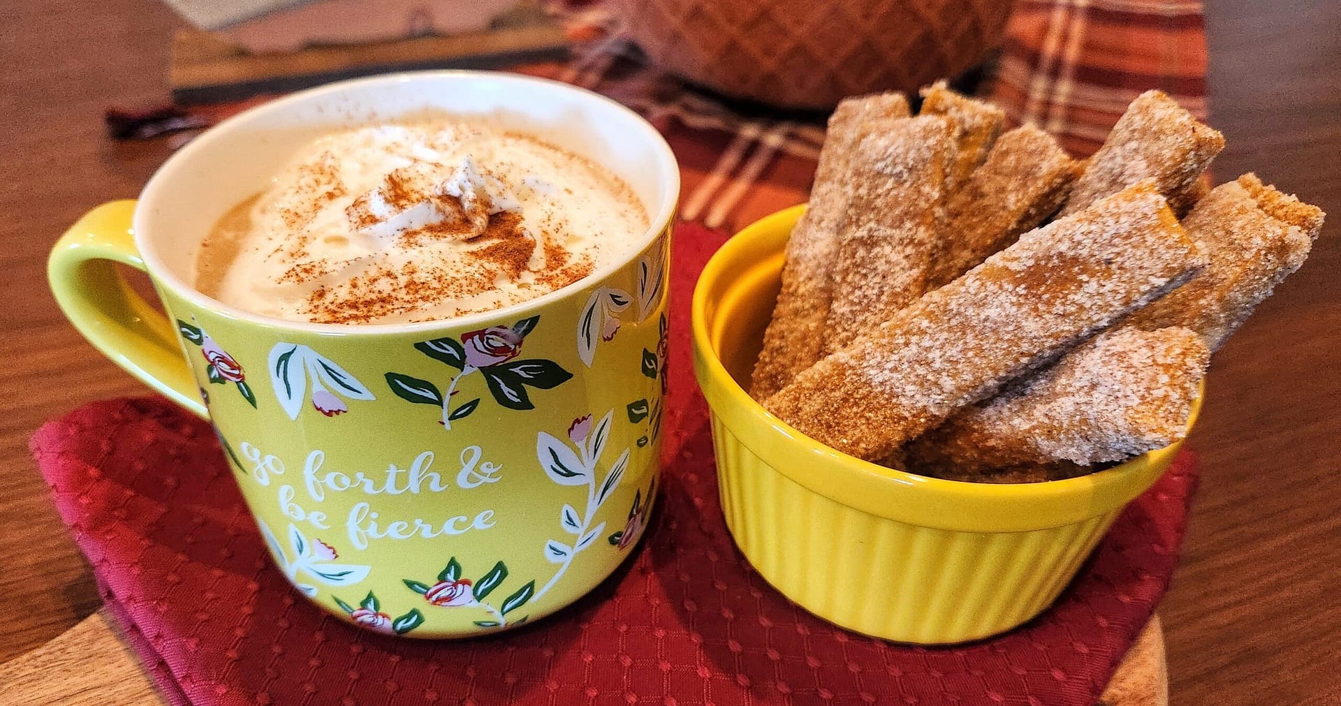 Pairing of a coffee styled with whipped cream with a bowl of cinnamon-sugar dusted cookies