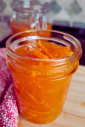 Half-pint mason jar of fresh orange marmalade with thin slices of orange peel and sticky jam