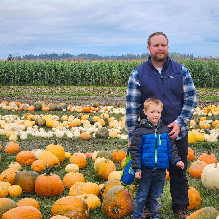 Father and son posing together in the pumpkin patch at Stocker Farms