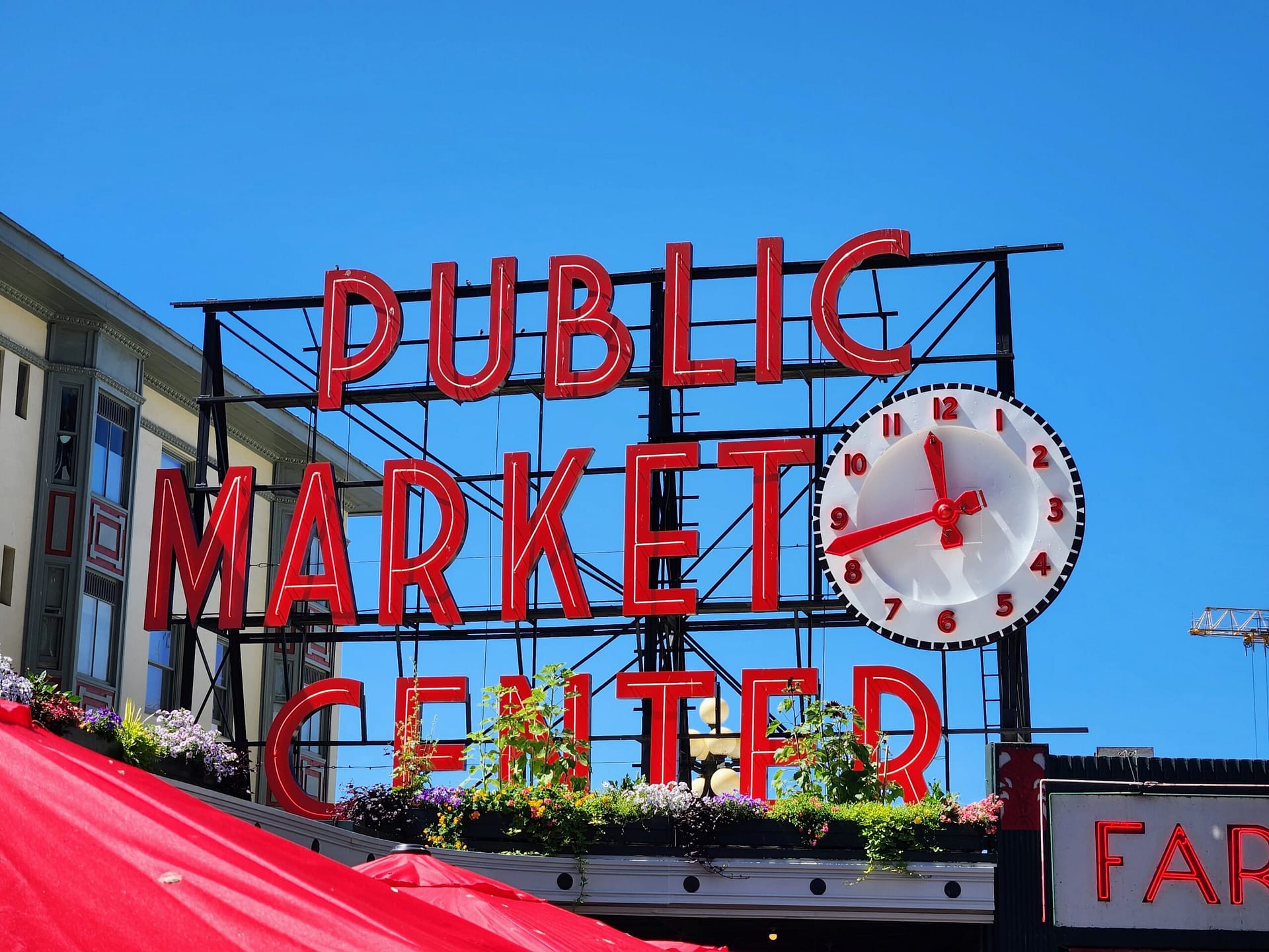 Pike Place Market sign with red umbrellas in the foreground and a blue sky background