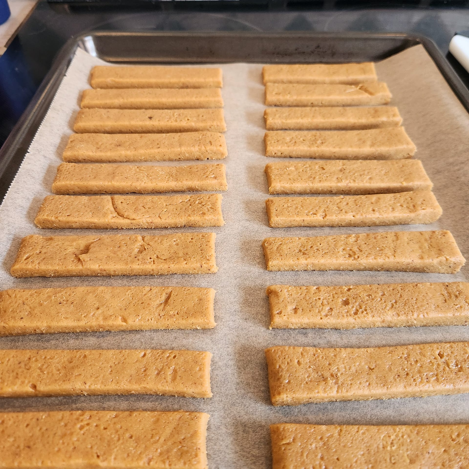 Pumpkin cookie sticks arranged on a baking tray