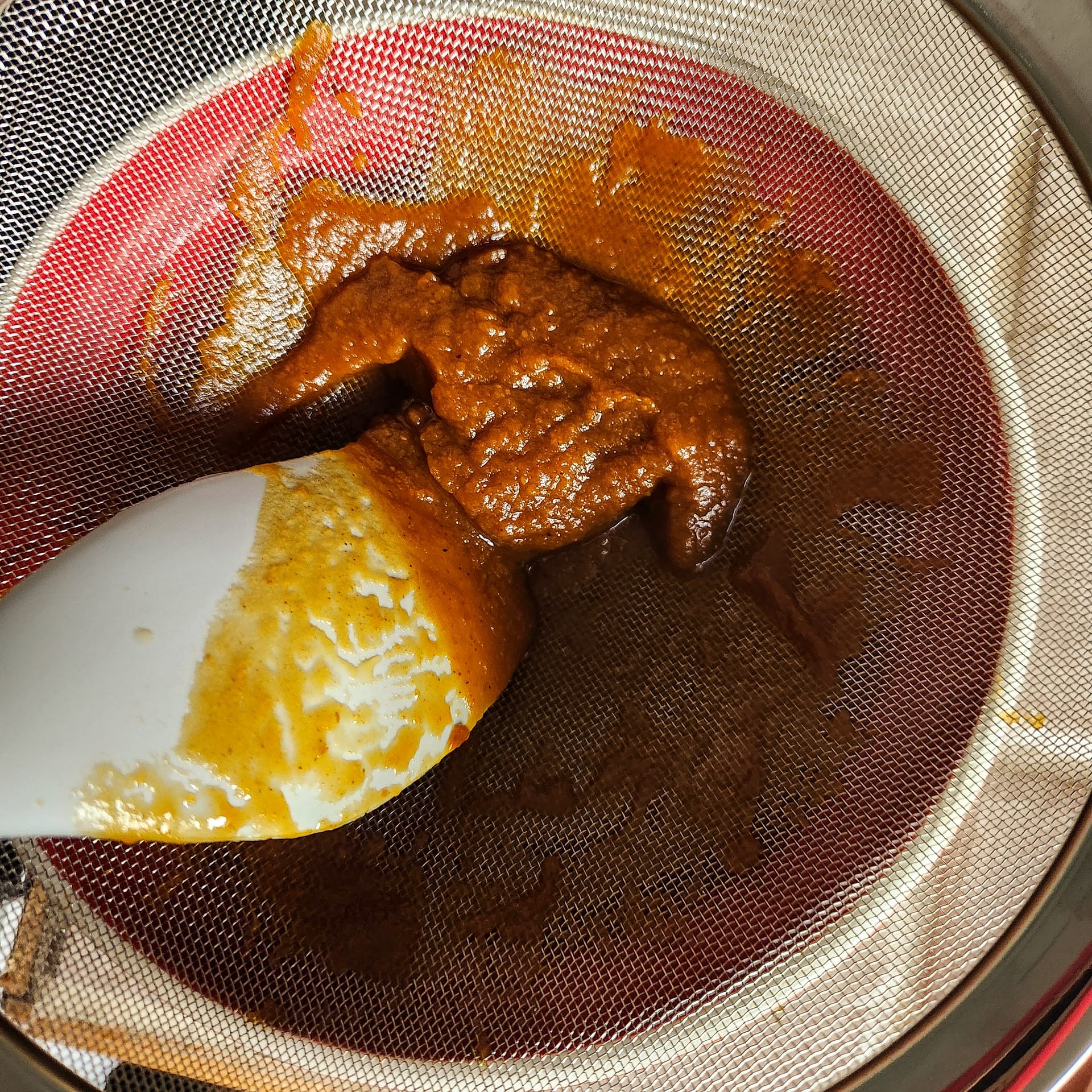 Pumpkin sauce being strained in a fine mesh strainer
